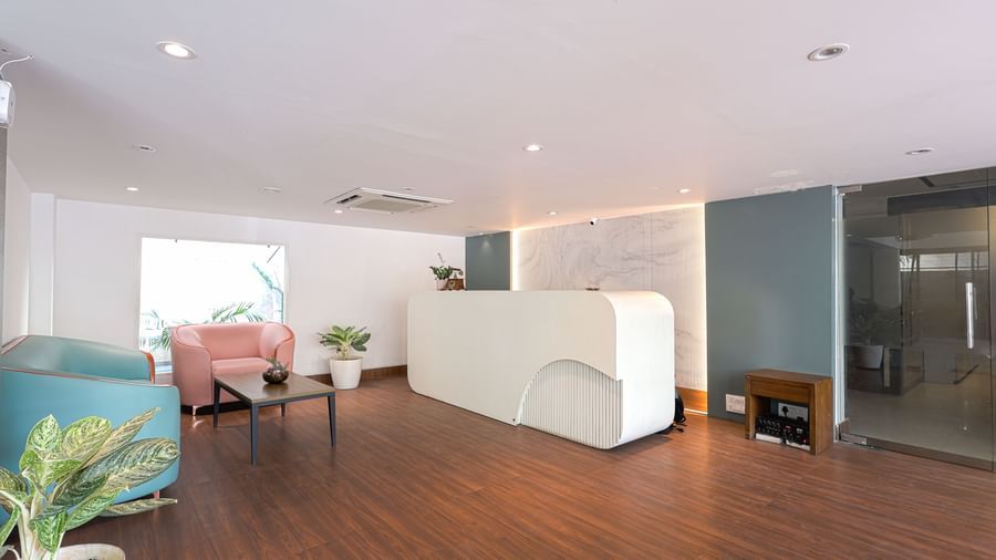 The brightly lit reception area of Destino by Monday Hotels, Gachibowli, with a modern white reception desk and comfortable seating.