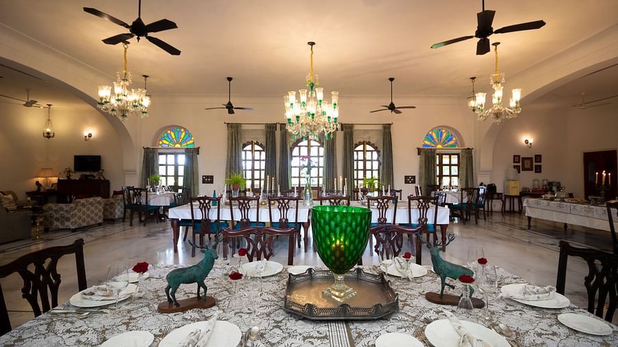 image of the indoor Dining arrangement at Dev Shree, deogarh with elegant chandeliers hanging from the ceiling