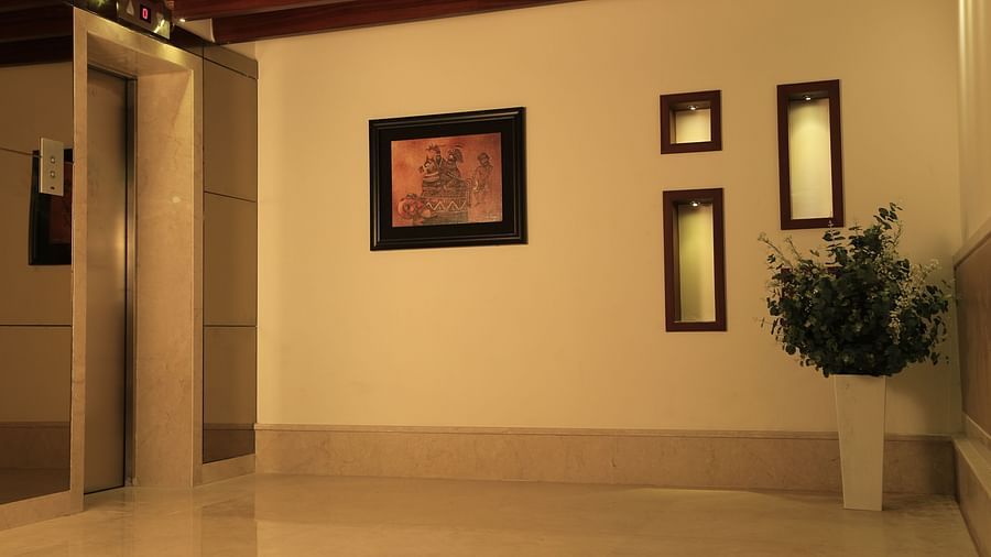 Side view of Orchid Hall at Dhanalakshmi Srinivasan Hotels, Perambalur with paintings on a wall and a plant.