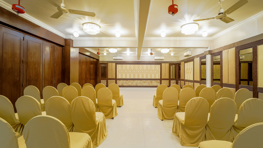 Rows of elegant chairs are set up in a bright room at Diamond Hotel Varanasi.