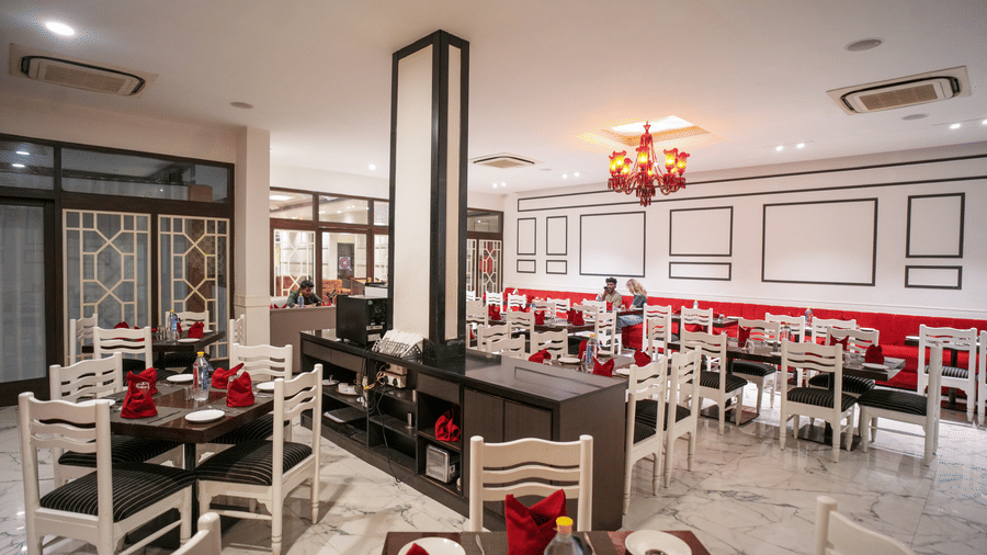 Diamond Hotel Varanasi's dining room offers a modern setting with tiled floors and neatly laid tables for guests.