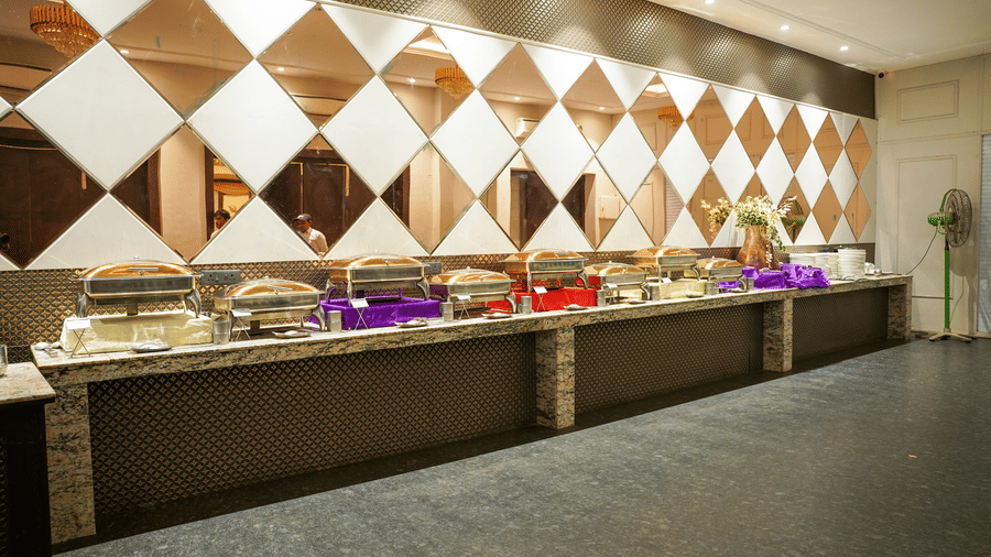 The buffet area at Diamond Hotel Varanasi features a long counter and a distinctive mirrored diamond wall design.
