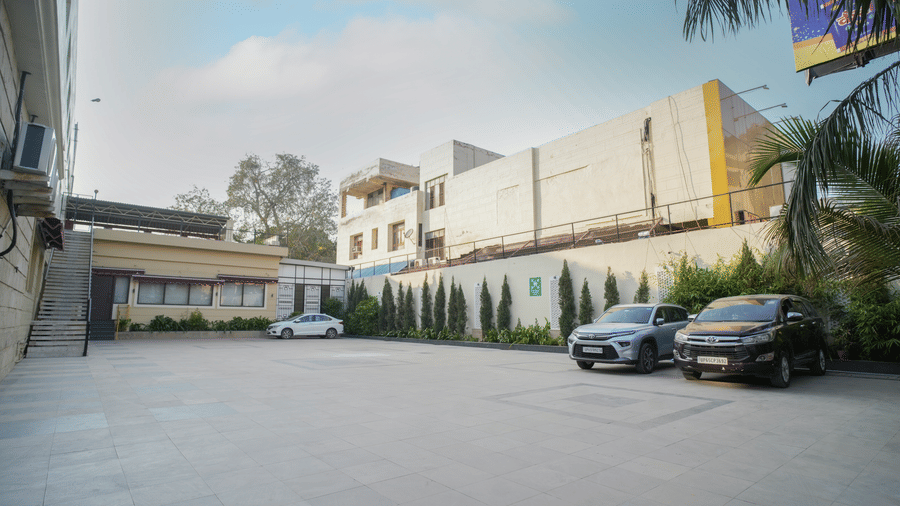 Cars are parked in the spacious, open-air secure parking lot of Diamond Hotel Varanasi under a clear sky.