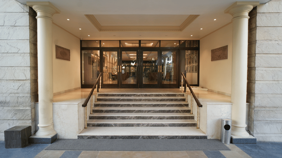 A wide set of steps leads to the glass entrance doors and pillared porch of the Diamond Hotel Varanasi.