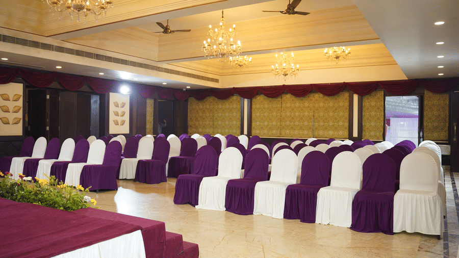 Rows of purple and white chairs face a stage at Diamond Hotel Varanasi, ready for a formal seminar or event.