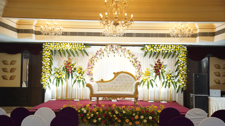 A floral wedding stage with a gold sofa and bright lighting awaits a celebration at Diamond Hotel Varanasi.