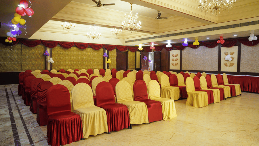 Red and gold draped chairs are neatly arranged in a spacious, festive function room at Diamond Hotel Varanasi.