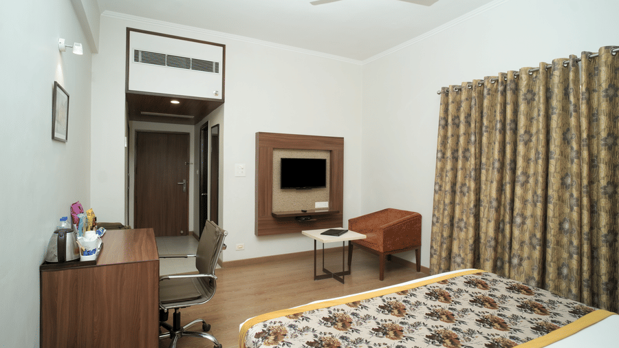 A tidy room at Diamond Hotel Varanasi comes equipped with a wall-mounted TV, a work desk, and air-conditioning.