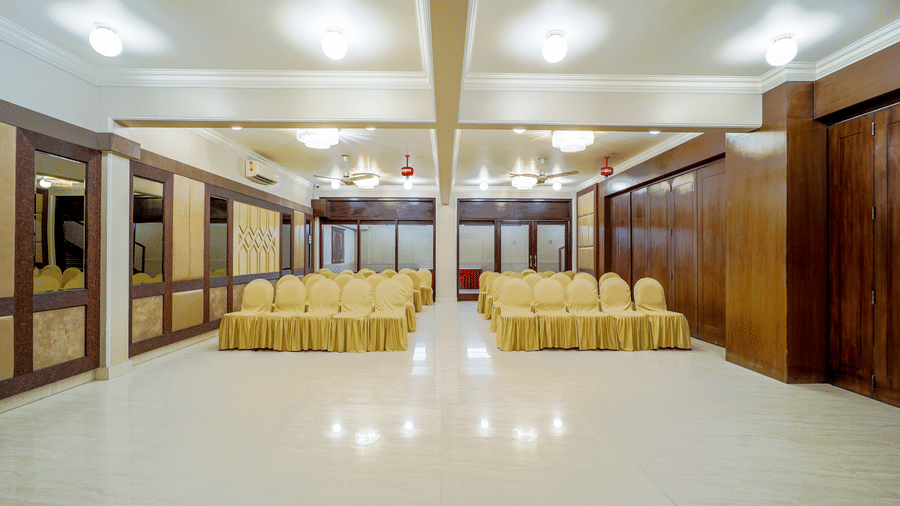 An elegant banquet hall features rows of yellow colour seating at Diamond Hotel, Varanasi.