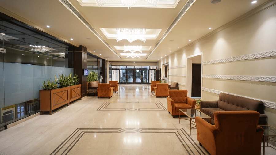 The bright, spacious lobby and lounge area at Diamond Hotel Varanasi features tiled floors and comfortable sofas.