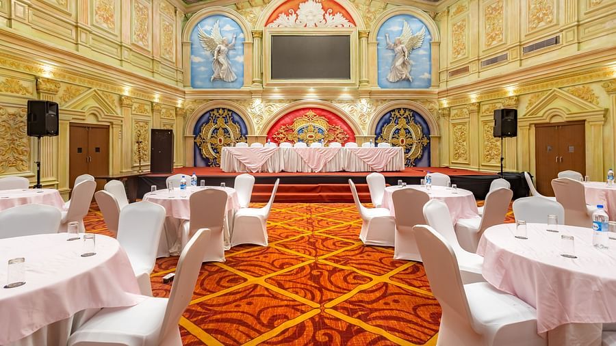 Elegantly decorated banquet hall at Diamond Palace Lords Plaza set with round tables and chairs facing a stage.