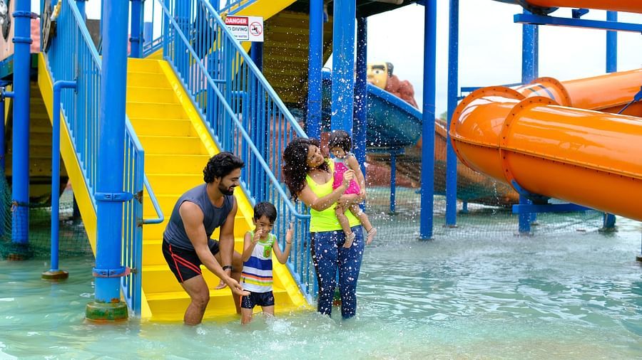 father helping his young child with a life jacket near water slides at a park | Diamond Parks, Pune 