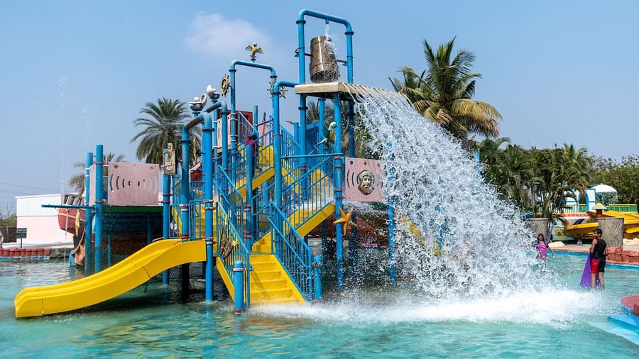 Children playing in a colorful water park with slides and large splash buckets, sunny day  | Diamond Parks, Pune