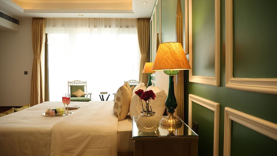 A room at Dileep Kothi, Jaipur with a double bed, side tables and a large window