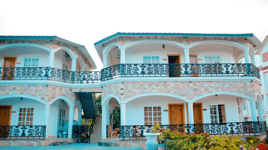 Facade of Dip Holidays, our hotel in Birbhum, in bright daylight highlighting the cyan coloured walls of the building .