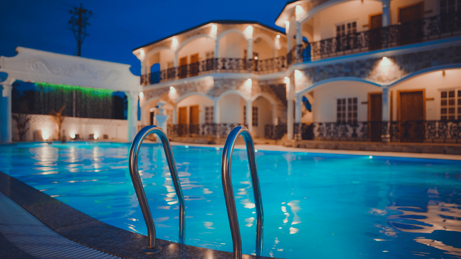 Night view of Dip Holidays featuring the stairs leading inside the swimming pool with the facade of the resort in the background.