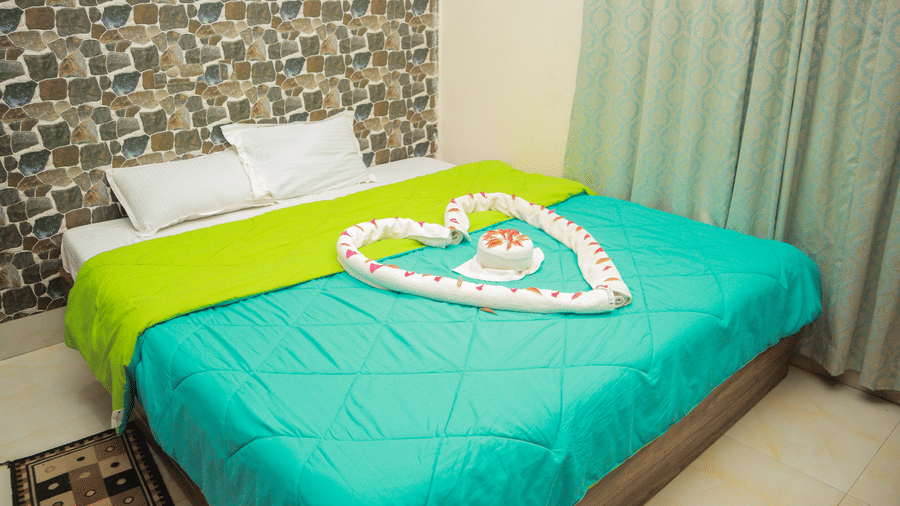Full view of the king size bed featuring the wallpaper behind it and the curtains in the side of the Standard Room at Dip Holidays.