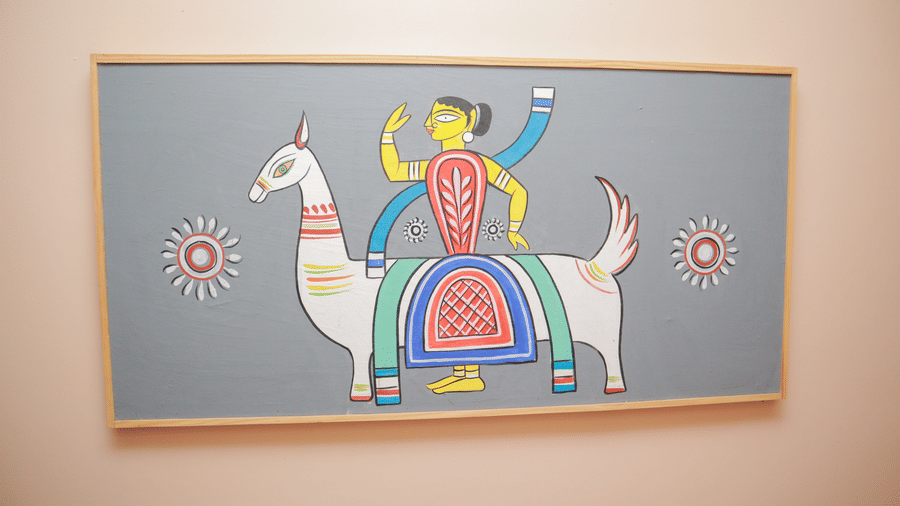 A traditional painting of a woman in a saree sitting on an animal hanging on a wall at Dip Holidays.
