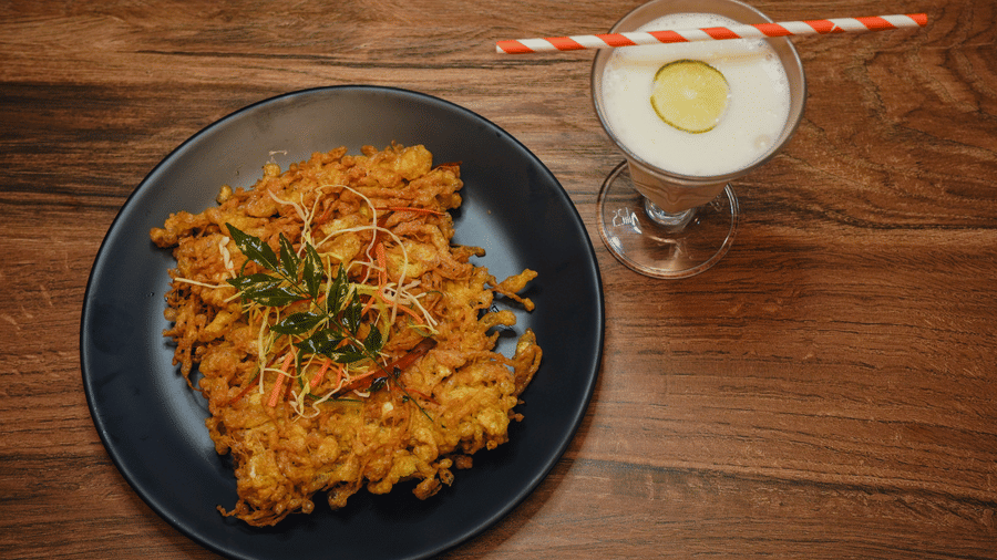 fried kobiraji bengali preparation topped with neem leaves served along a refreshing lime beverage .