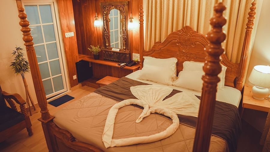 image of a cosy bedroom featuring a king size bed with a bed side table lamp brightening the room with warm lighting
