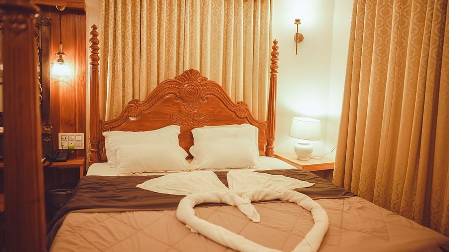image of a king size bed with a grey and brown coloured comforter spread over it in a brightly lit bedroom