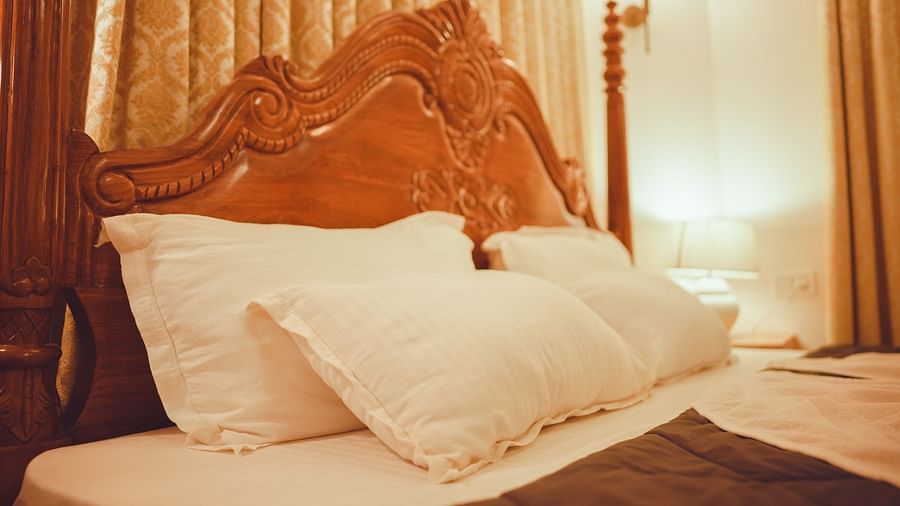 a close up image of the pillows set againsta a polished wooden head board 