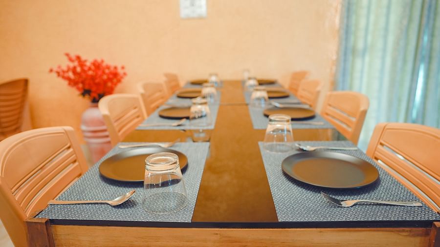 a close up image of the dining table at mache vate bangali featuring set plates and cutlery placed over table mats - Dip Holidays, Birbhum
