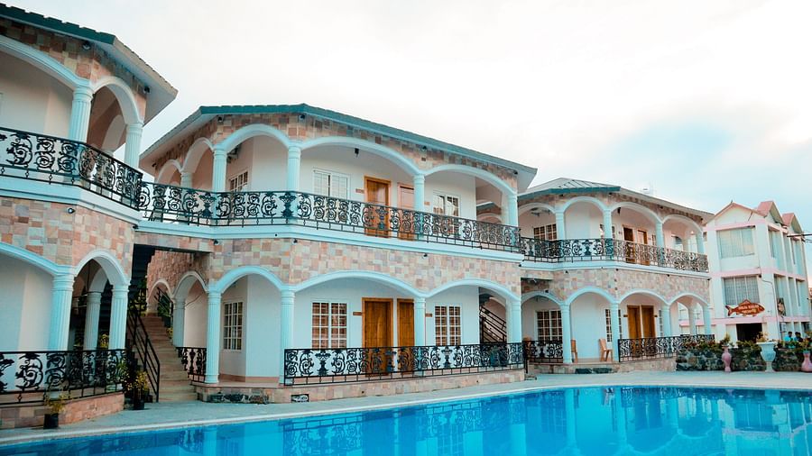 facade image of dip holidays in birbhum from a different angle featuring cyan coloured building with black metal railings