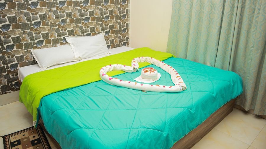full view of the king size bed featuring the wallpaper behind it and the curtains in the side of the room