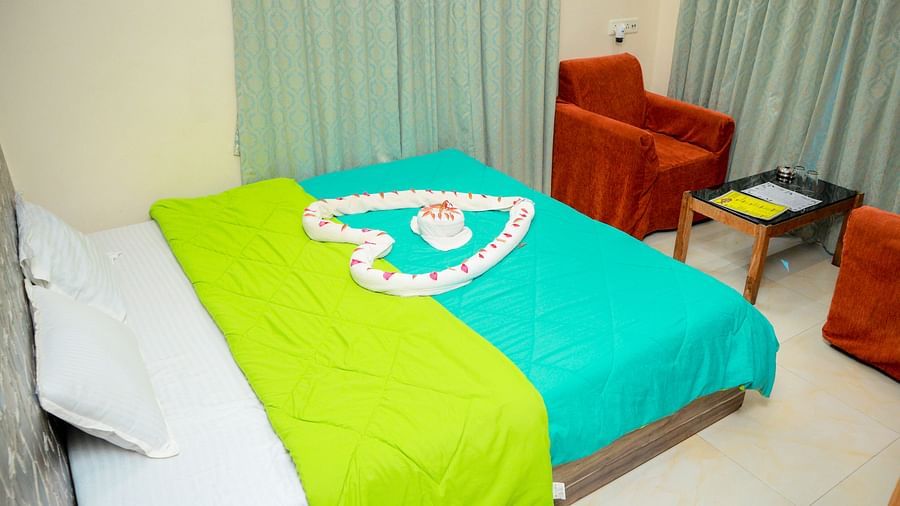 image of a king size bed with a heart shaped decoration over it with flower petals and a family seating area in the corner