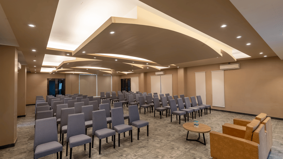 Banquet halls in Jim Corbett at DLS Forest Vines Resort, with cushioned seating arranged on both sides, a plush sofa, and a table placed in front.