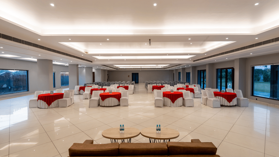 Tables with neatly decorated tablecloths, a plush sofa, and two round tables set in front at DLS Forest Vines Resort | Banquet Halls in Jim Corbett