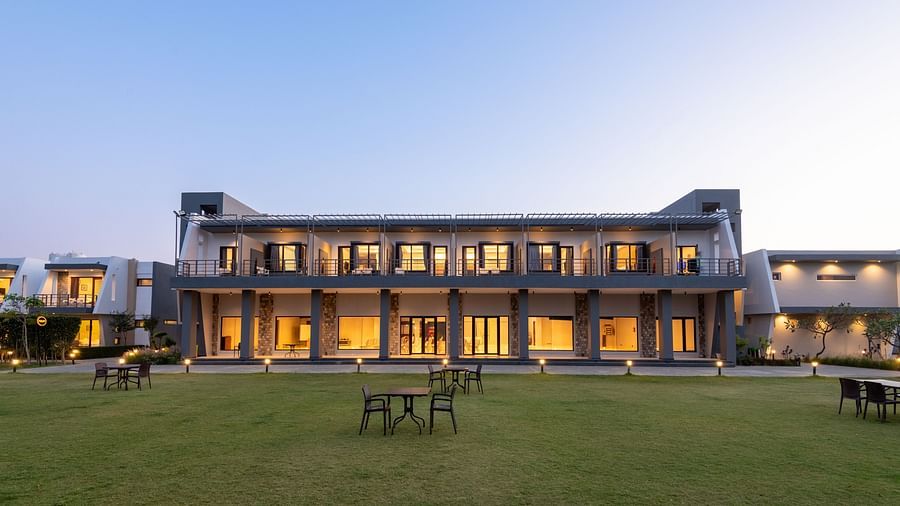 Facade view of DLS Forest Vines Resort, illuminated by warm lights from the windows and doors.