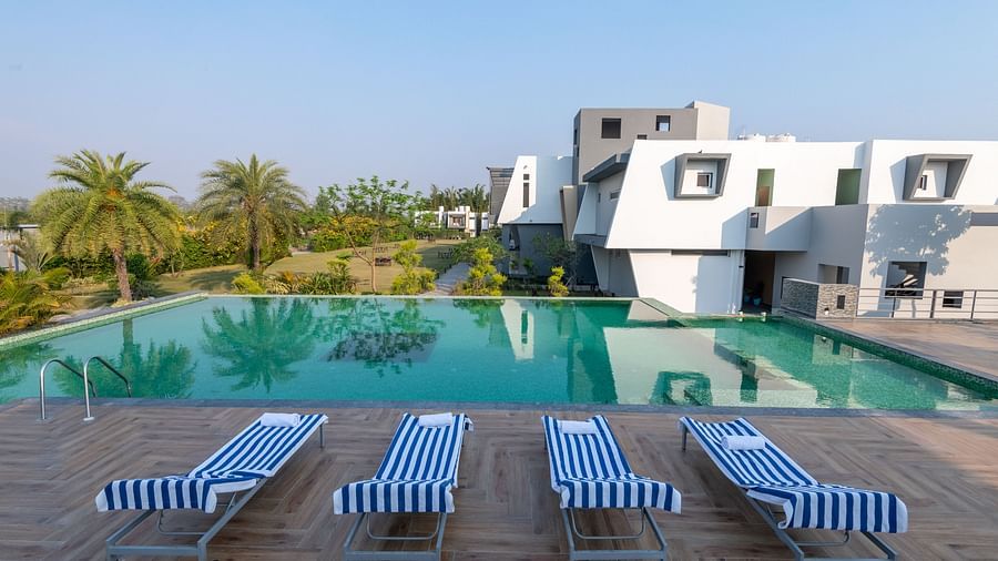 Pool area with lounge chairs placed beside it, offering a view of trees on one side at DLS Forest Vines Resort.