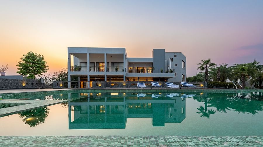 Facade view of DLS Forest Vines Resort with its reflection shimmering on the swimming pool under a clear sky.