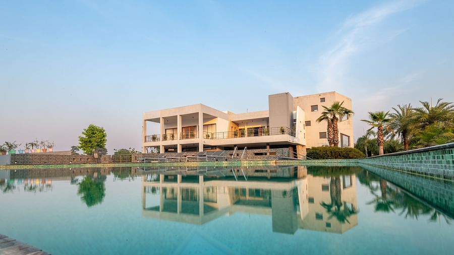 Facade view of DLS Forest Vines Resort with its reflection shimmering on the swimming pool under a clear sky.