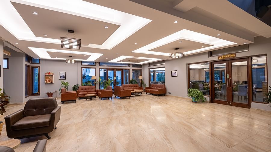 Reception area at DLS Forest Vines Resort, seen from the far end, featuring bright lighting and clean, cushioned sofas.