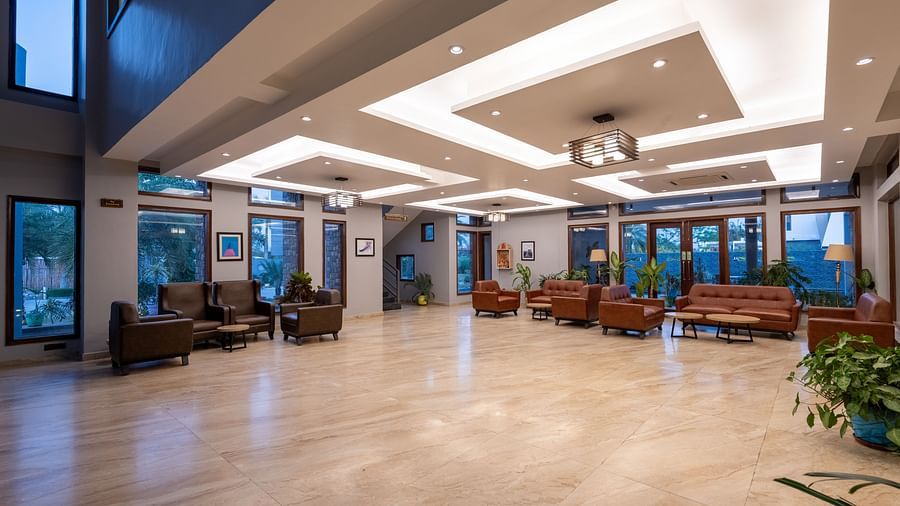 Reception area at DLS Forest Vines Resort, seen from the far end, featuring bright lighting and clean, cushioned sofas.