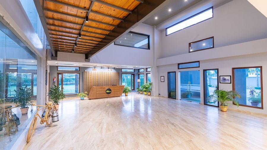 Reception desk at DLS Forest Vines Resort, located at the far end of the hall, featuring wooden ceiling interiors and bright lighting.