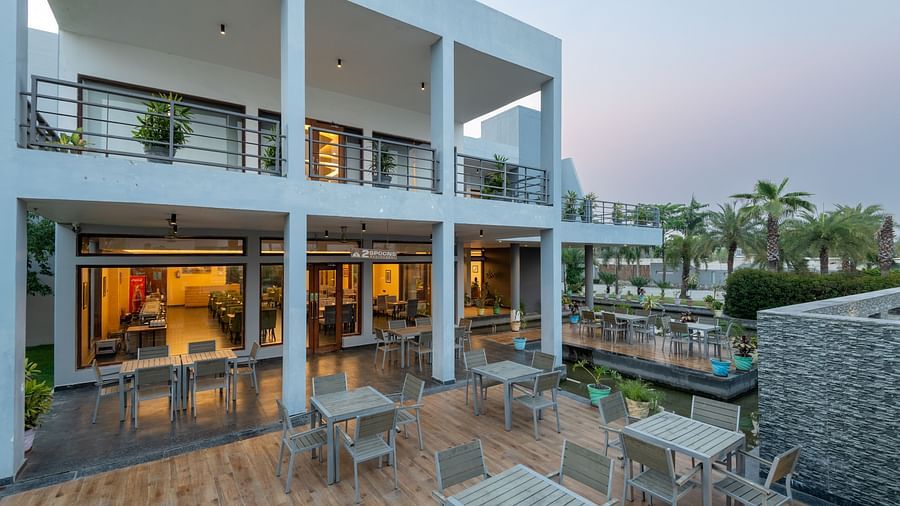 The facade of DLS Forest Vines Resort, glowing with warm light spilling from the windows and doors.