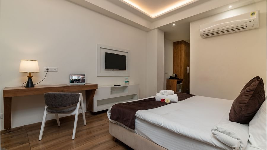 An image of a deluxe room with a work desk, chair, bed, flat screen TV, and other room amenities - DLS Ganga Bliss, Haridwar