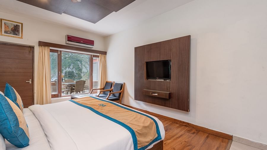 Side view of Premium Room at DLS Spring Valley Resort Dharamshala featuring a king size bed, chair and a balcony