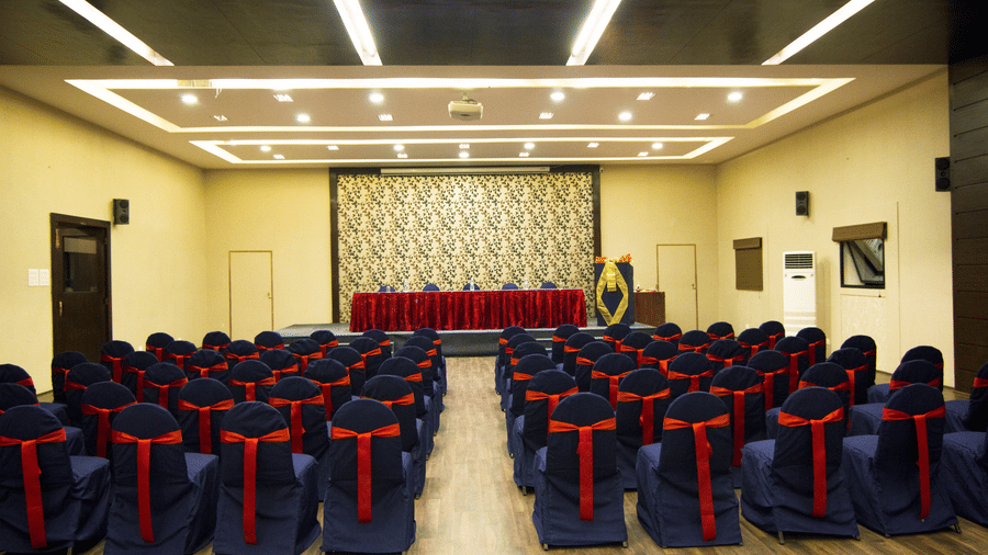 Theatre-style seating in a banquet hall at DNC Shevaroys Resort & Spa, featuring clothed chairs facing a raised stage area.