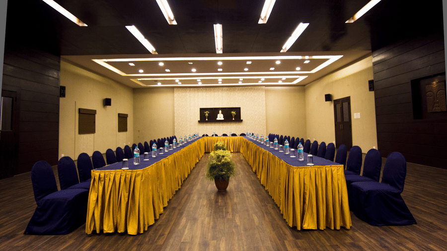 A formal meeting room at DNC Shevaroys Resort & Spa with a U-shaped table covered in fabric and surrounded by chairs.