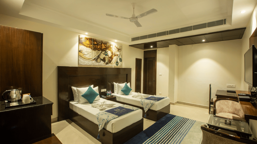A modern superior room featuring two twin beds with blue and white striped runners and contemporary wall art — Eastlynn Resort, Rishikesh