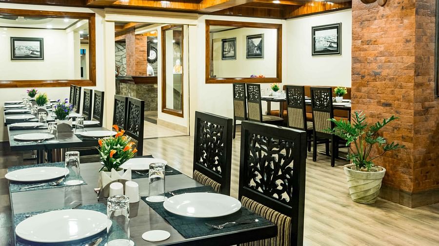 An image of a restaurant with seating arrangement and tables laid out with plates and cutlery - Ecotel Tin Tin, Bijanbari