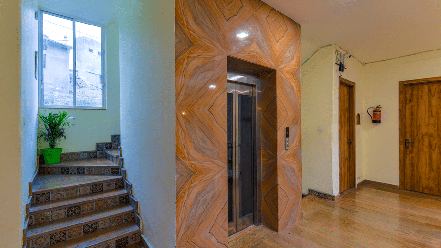 Interior with staircase, wooden wall design, lift, and corridor, at Ewaka Ganga, Rishikesh.