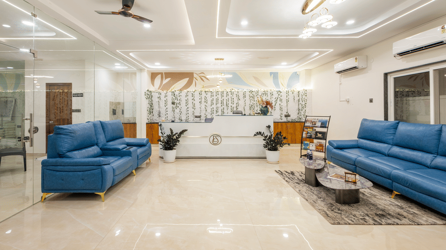 A living room at Elysium Studio Suites, Madhapur, contains blue sofas and light fixtures on the ceiling.