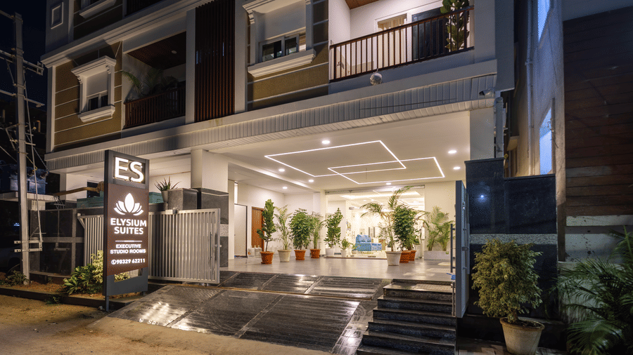 The entrance area of Elysium Studio Suites, Madhapur, is shown at night with steps leading up to the main door.