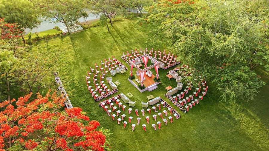 Aerial view of an elegant setting of chairs facing towards the stage in a lawn on a sunny day at Essentia Luxury Resort & Spa, Udaipur. 